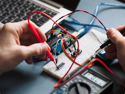 Hands working with electronics and multimeter.