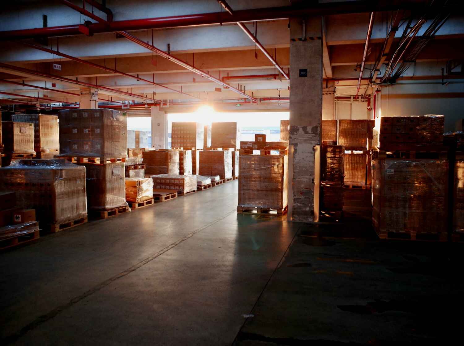 Warehouse with stacked pallets, sunlight streaming in.