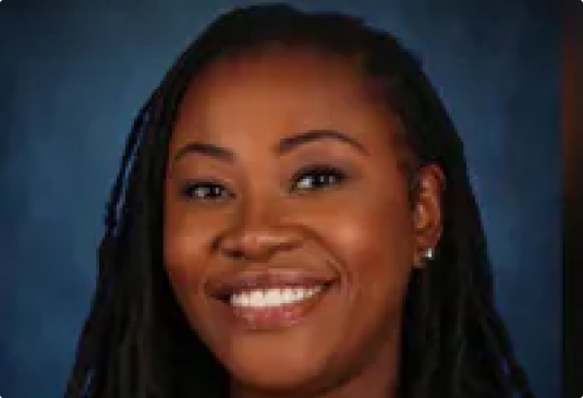 Smiling person with long hair, blue background.