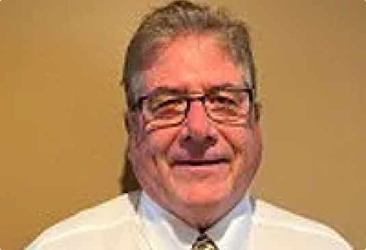 Smiling man in glasses and white shirt.