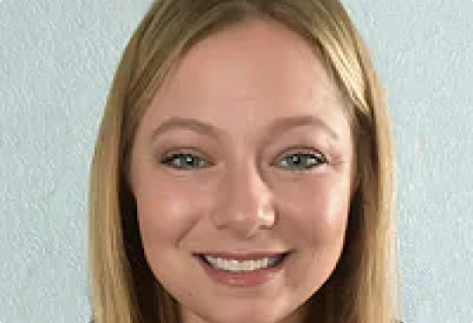 Smiling person with straight hair against plain background.